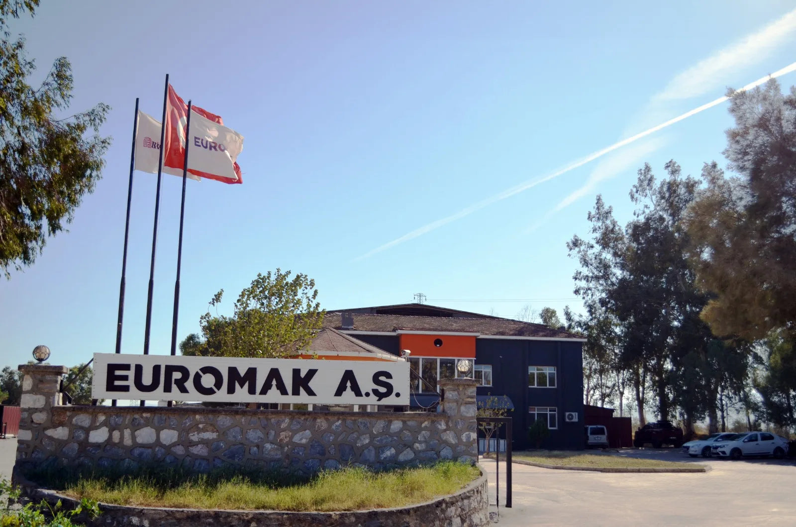 EUROMAK A.S. building with sign and flags against a clear blue sky
