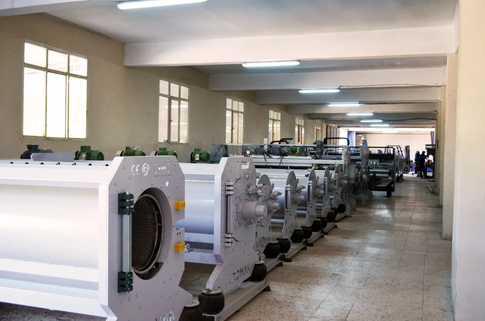 Long rows of rug spinner machines in a factory setting